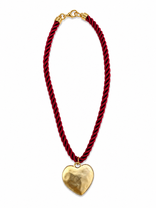 A twisted red cord necklace with a polished gold heart pendant, displayed on a clean white background.