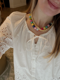 Person wearing a colorful beaded necklace and a white blouse with lace details. – view 2