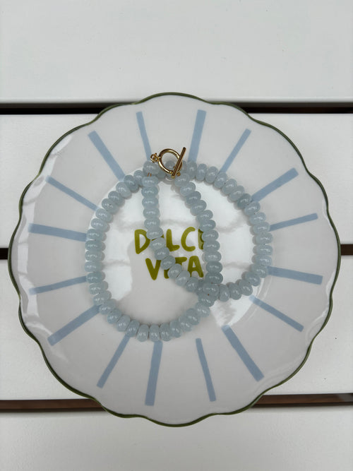 blue beaded necklace on a decorative plate with 'Dolce Vita' text.